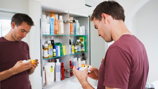 A man taking an item out of his medical cabinet. 