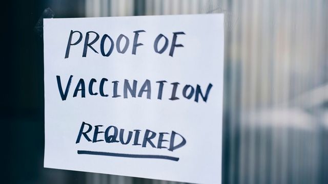 A sign listed on a window that reads "proof of vaccination required". 