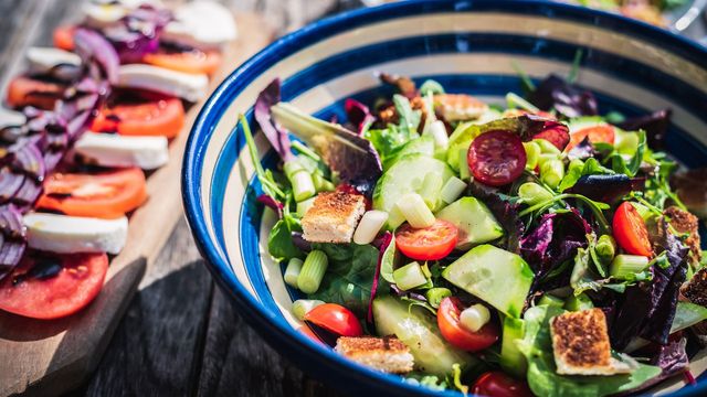 A salad in a blue and white striped bowl. 