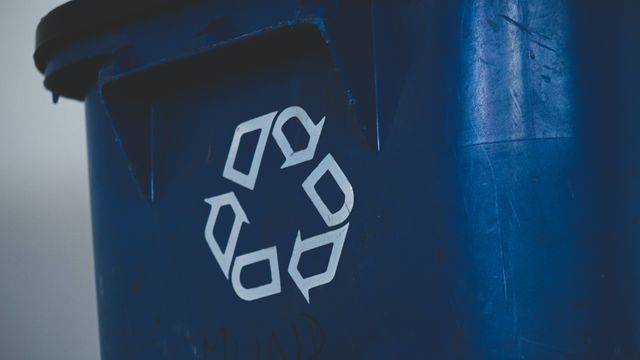 A recycling bin with the triangle recycling logo on the front. 