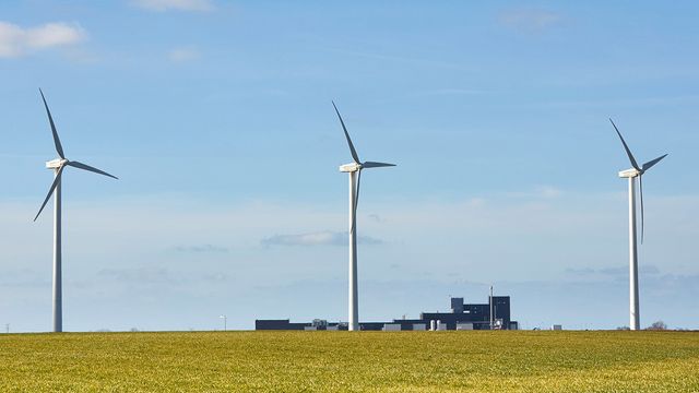 Three wind turbines in a row in a field. 